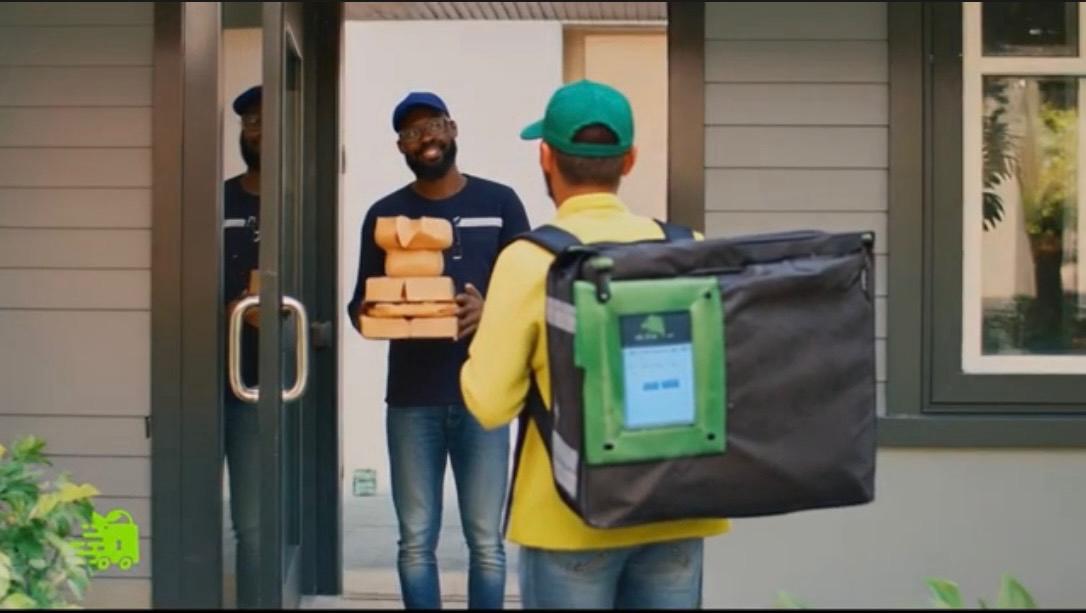 Delivery courier handing sealed order at customer door